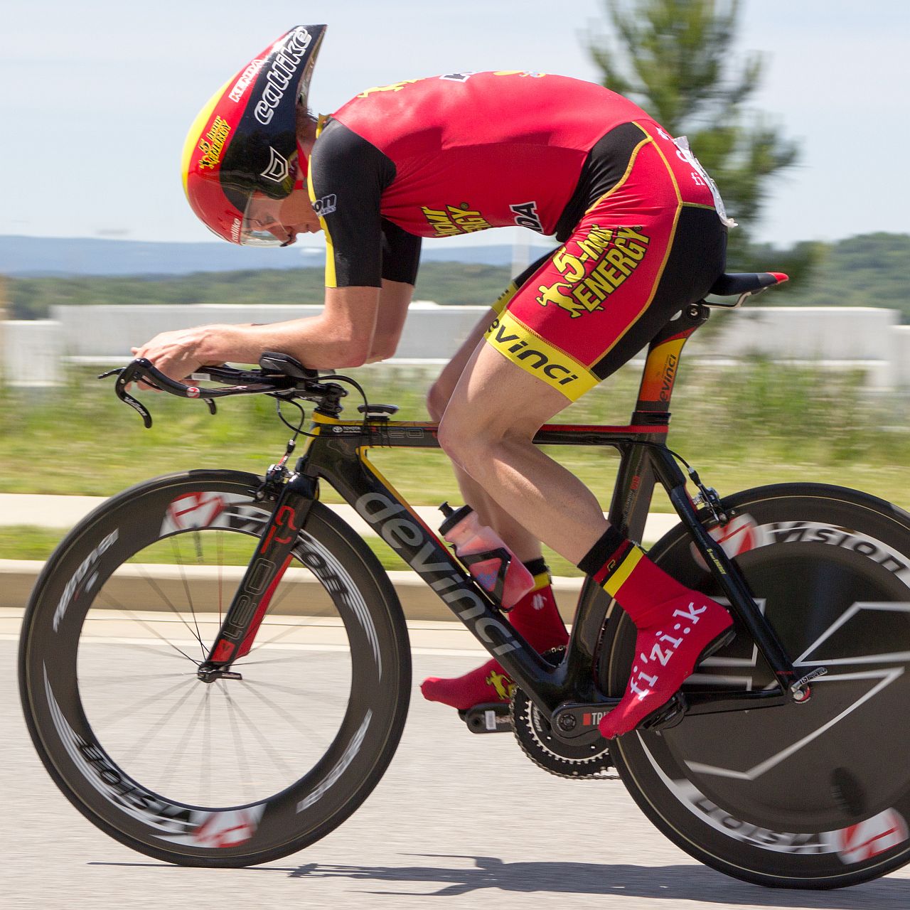 the man is riding his bike while holding onto his helmet