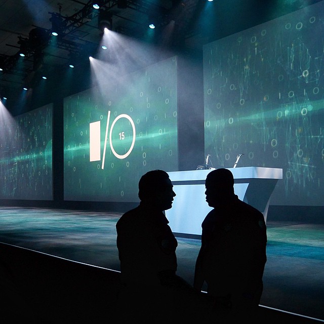 two men sitting in front of a stage and projected images