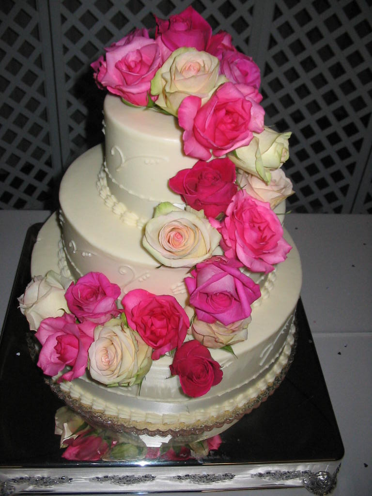 a wedding cake with pink roses on top