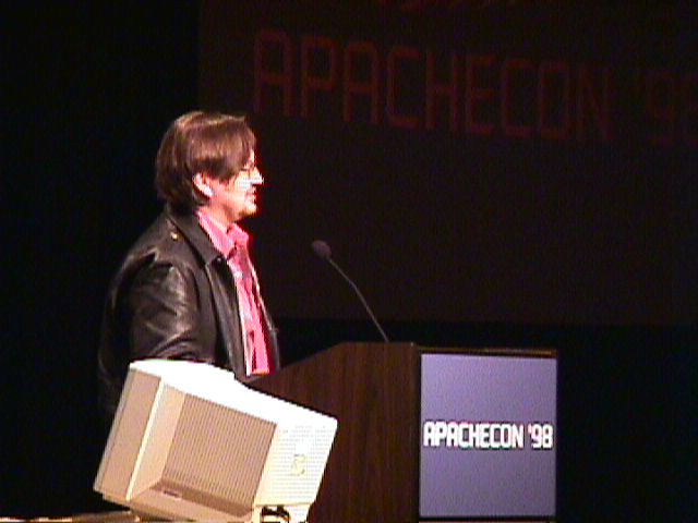a man standing at a podium behind a projection screen