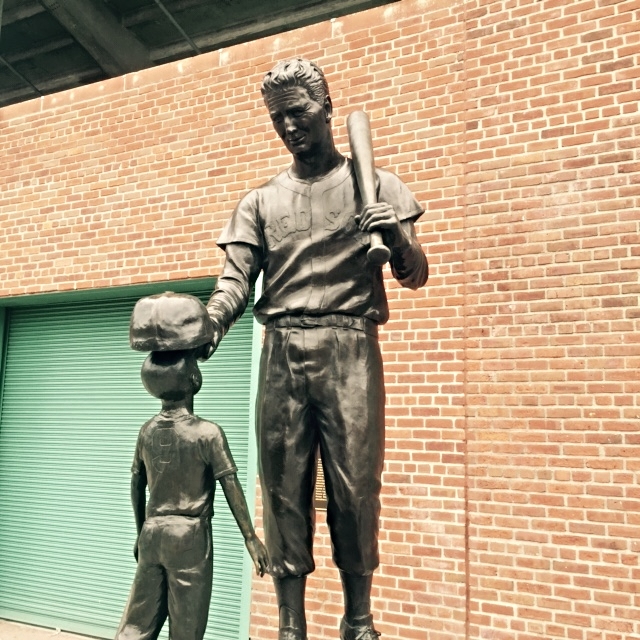 a metal statue of a man with a baseball bat and boy