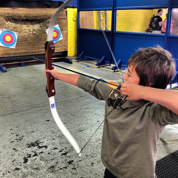 a little boy hitting a bow at an archery range