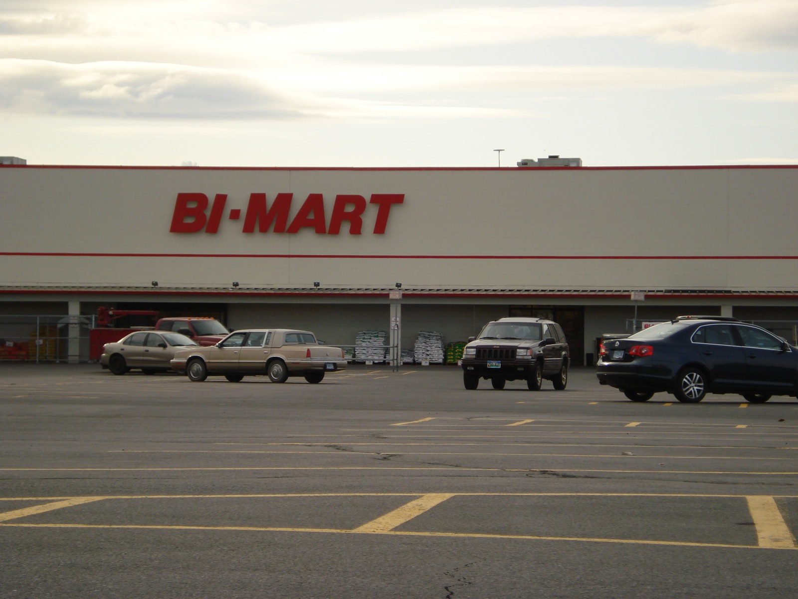 cars parked outside a bj mart store with vehicles parked on the lot