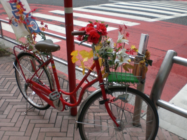 red bike parked next to pole with flowers in basket