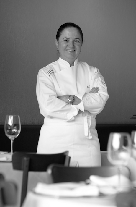 a chef wearing a white uniform stands near table with glasses