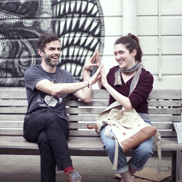 man and woman sitting on park bench making funny faces