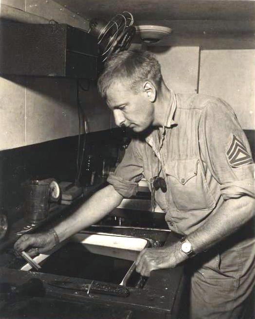 an old time po shows a sailor working on a stove