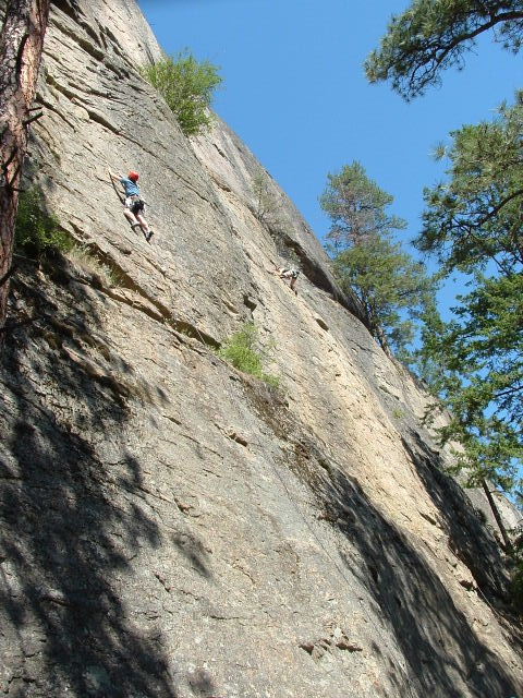 a climber climbing on a steep mountain with trees