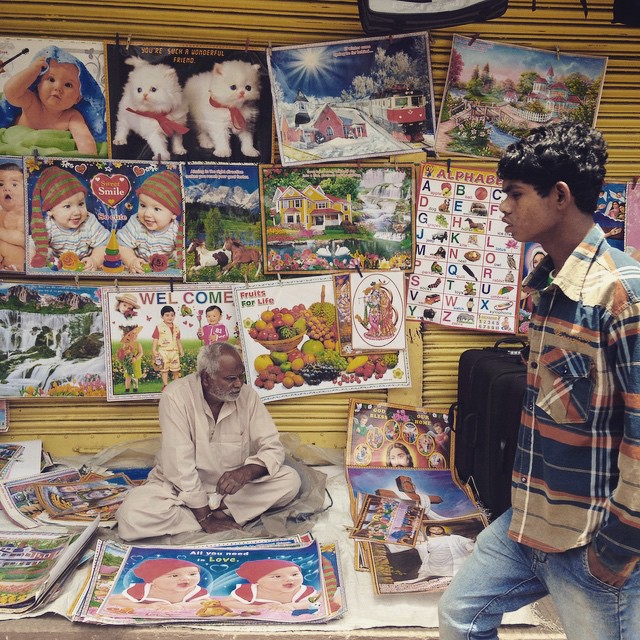 two men looking at posters and a book shelf