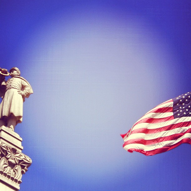 a tall statue is next to a flag