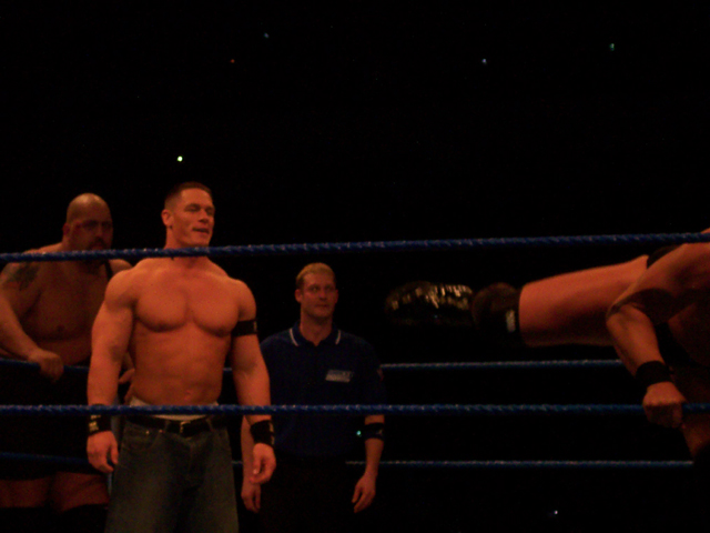 two men and one man with  are in the ring wrestling