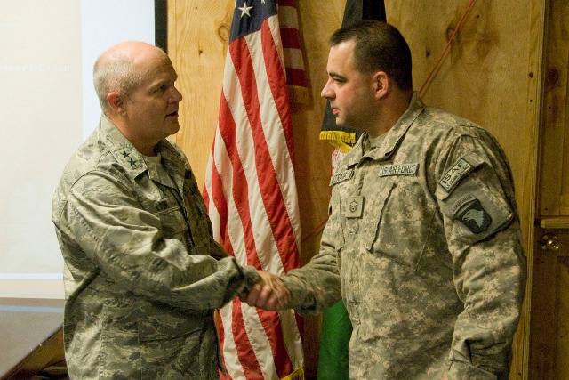 two soldiers shake hands in front of the american flag