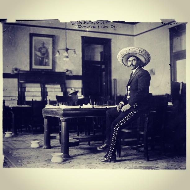 an old pograph of a mexican lady in a suit and hat