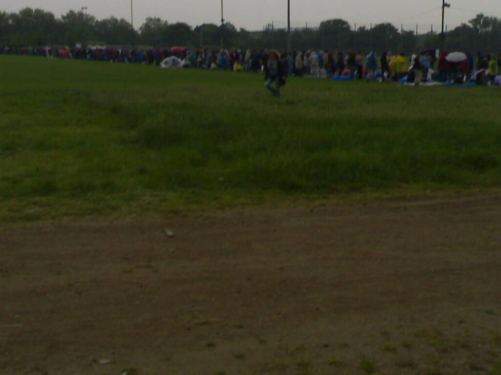 people standing in a field with tents, and umbrellas