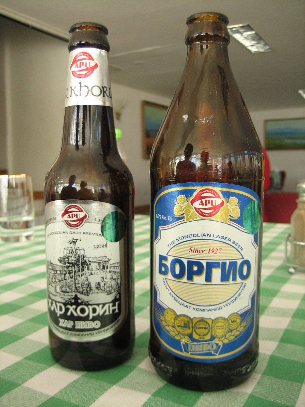 two beer bottles next to each other on a green and white tablecloth