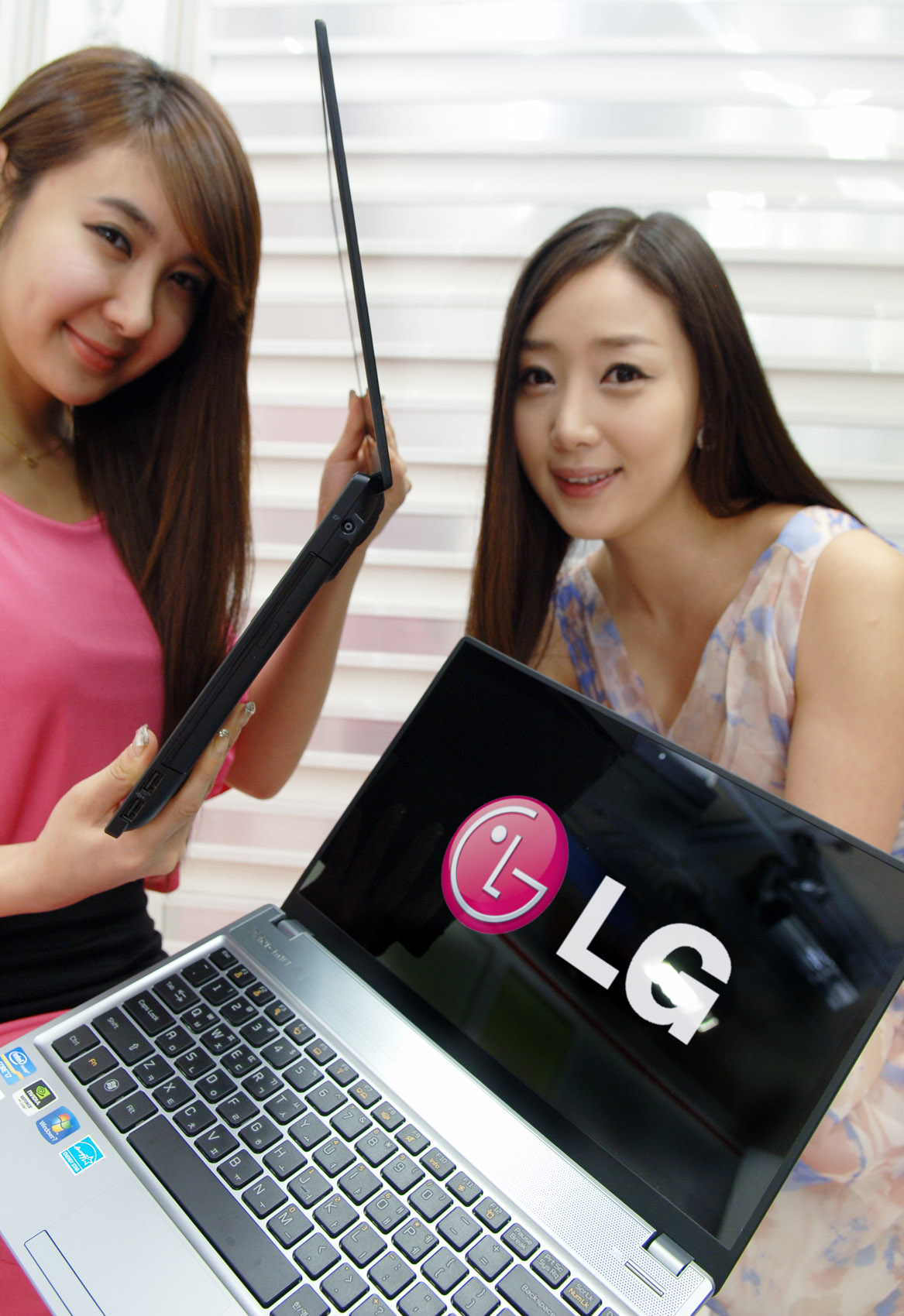 a couple of pretty young ladies holding up an lg laptop