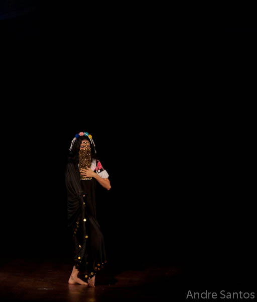 woman wearing dark clothing and veil standing alone with black background