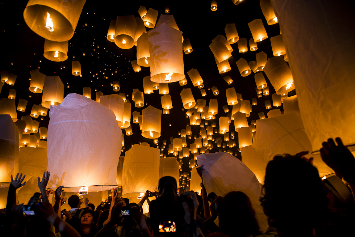 people are flying lanterns in the air