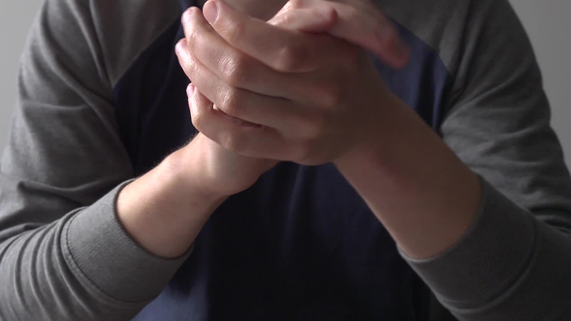 a man with hands folded while holding his hands together