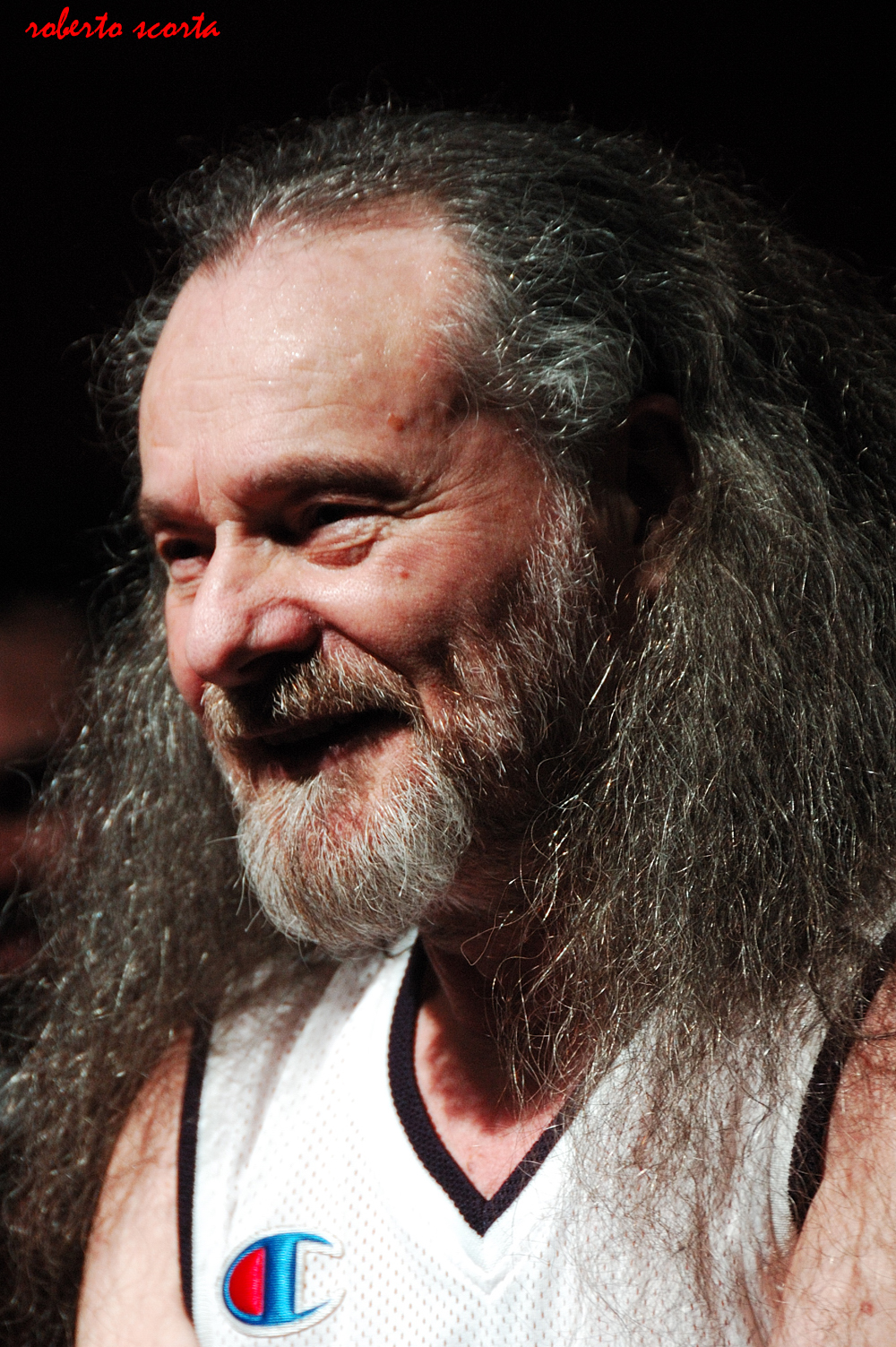 a basketball player with long, gray hair and beard smiling