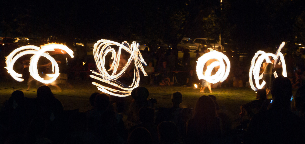 fire show being performed on the ground with people watching