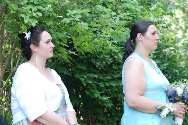 two women in blue dresses are standing outdoors