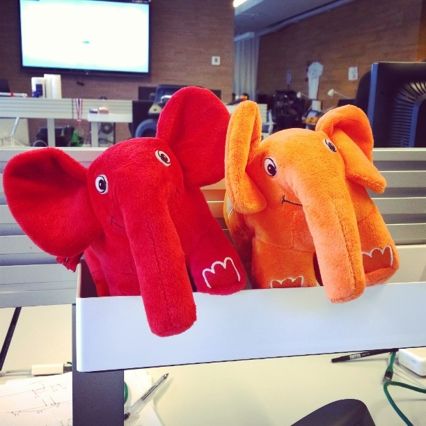 two orange elephants are in a row with one sitting on the shelf