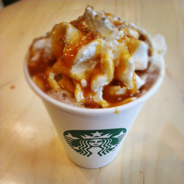 a foam cup with a caramel sauce, toppings and a starbucks cup logo