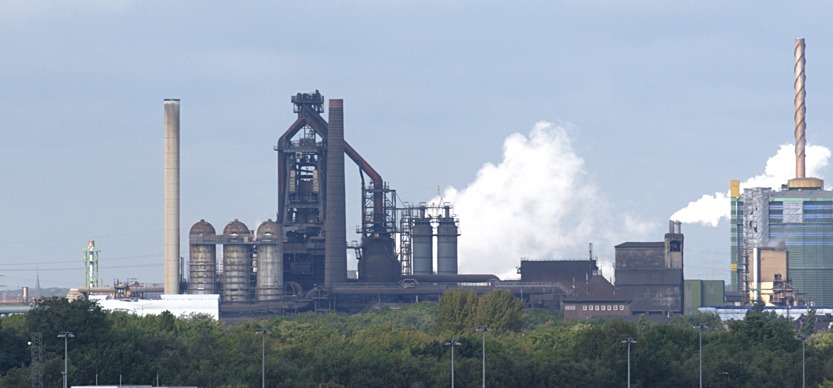 factories and trees with smoke stacks in the background