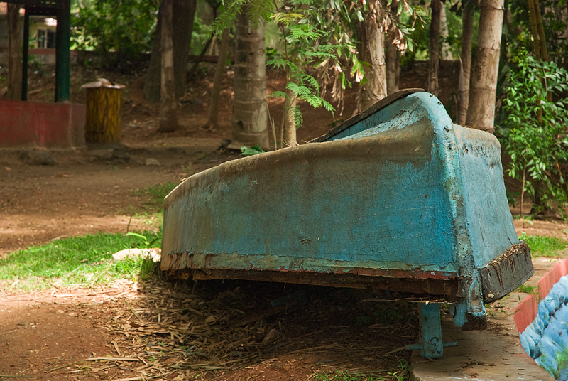 an old, rusted blue covered bed sits in the dirt