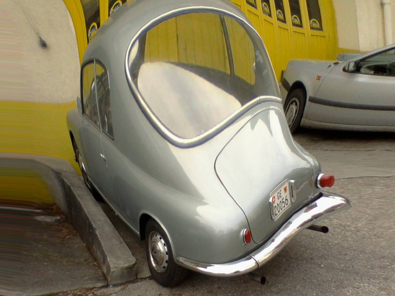 an old style silver car is parked in the street