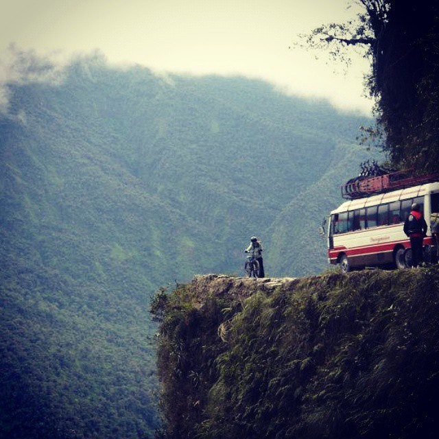 two people on a bike standing next to a van