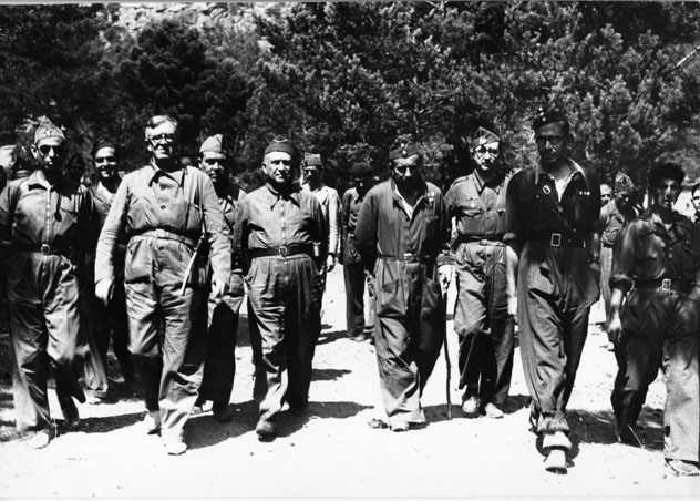 a group of men who are wearing uniforms walking down a street