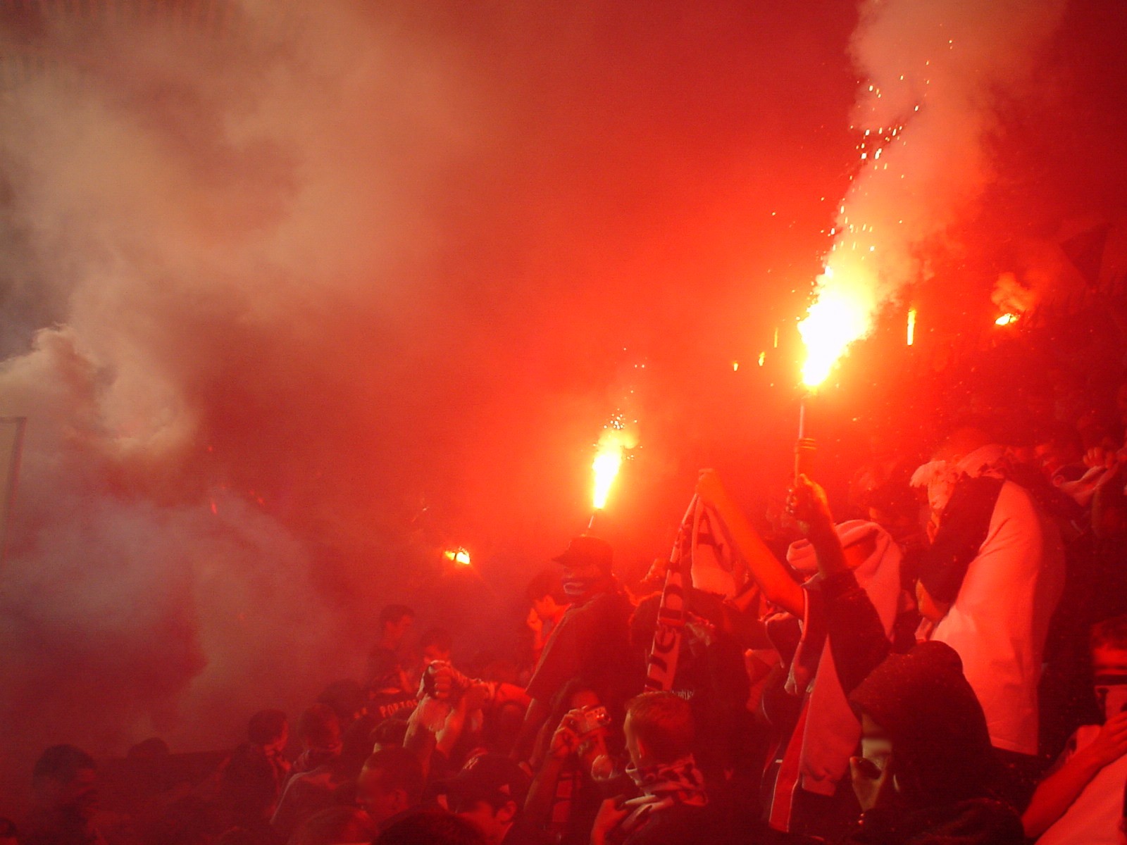 many people holding their arms up in the air near flares