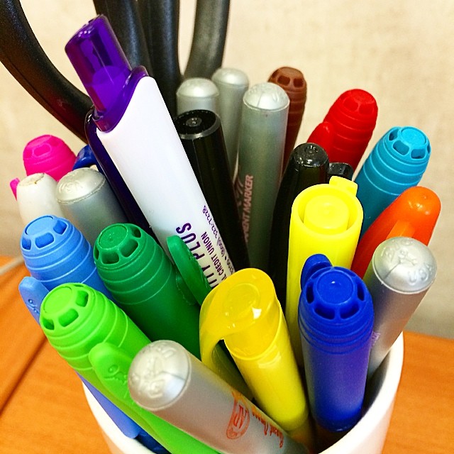 a plastic cup filled with pens and markers
