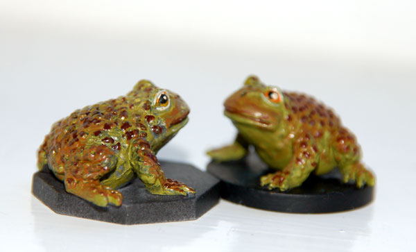 two frogs sitting on some black bases next to each other