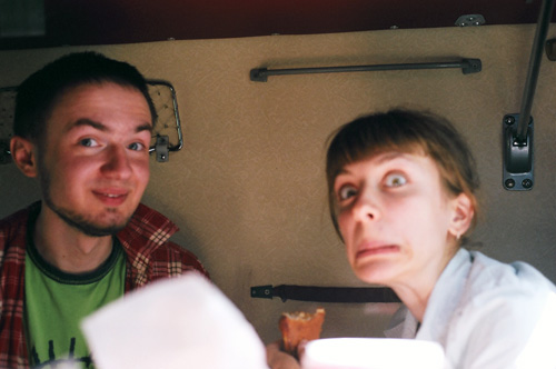 two people with plates looking surprised on a train