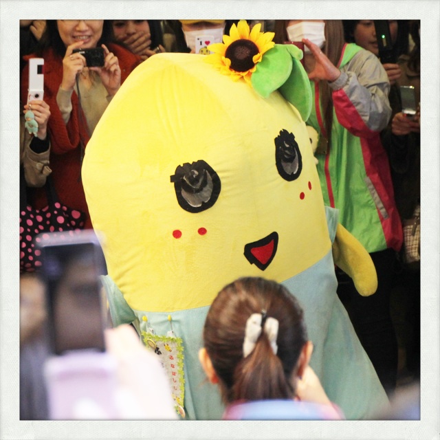 a person wearing a large yellow costume standing next to a crowd