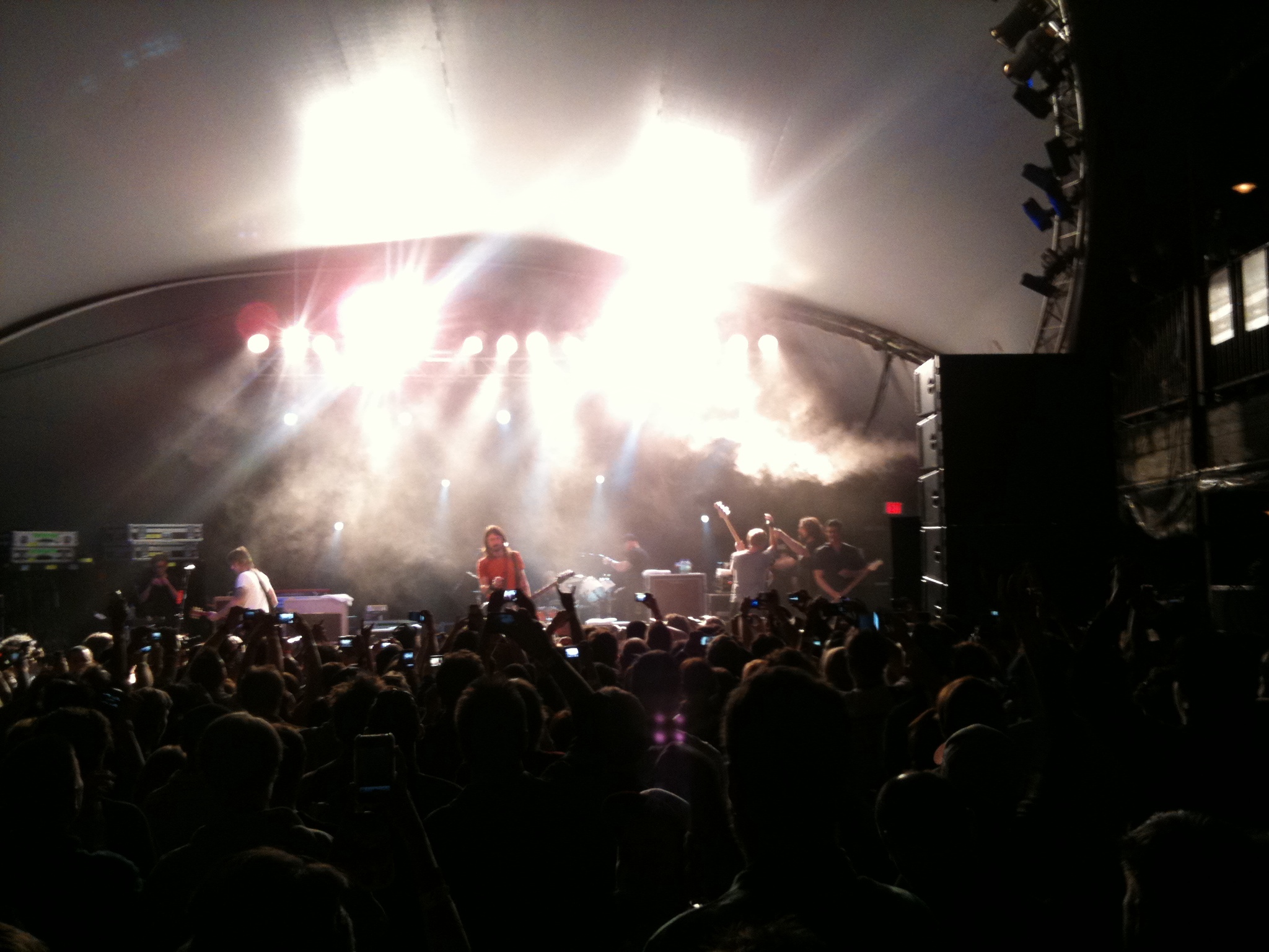 an outdoor concert with some light shining on the stage