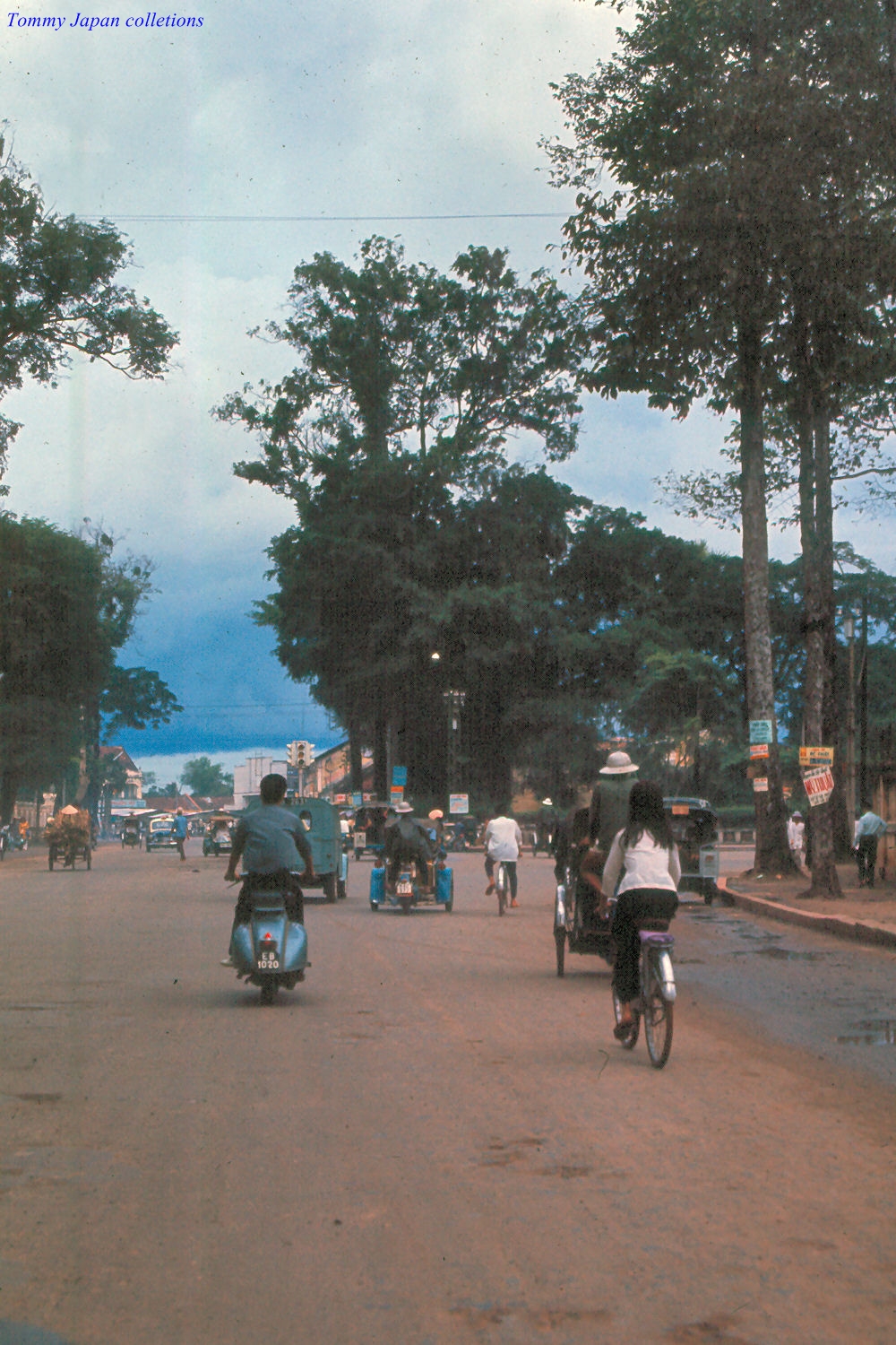 a view down a street as people ride bikes and motorcycles