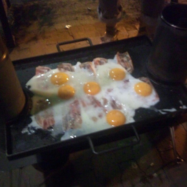 eggs and bacon on a griddle of  coals