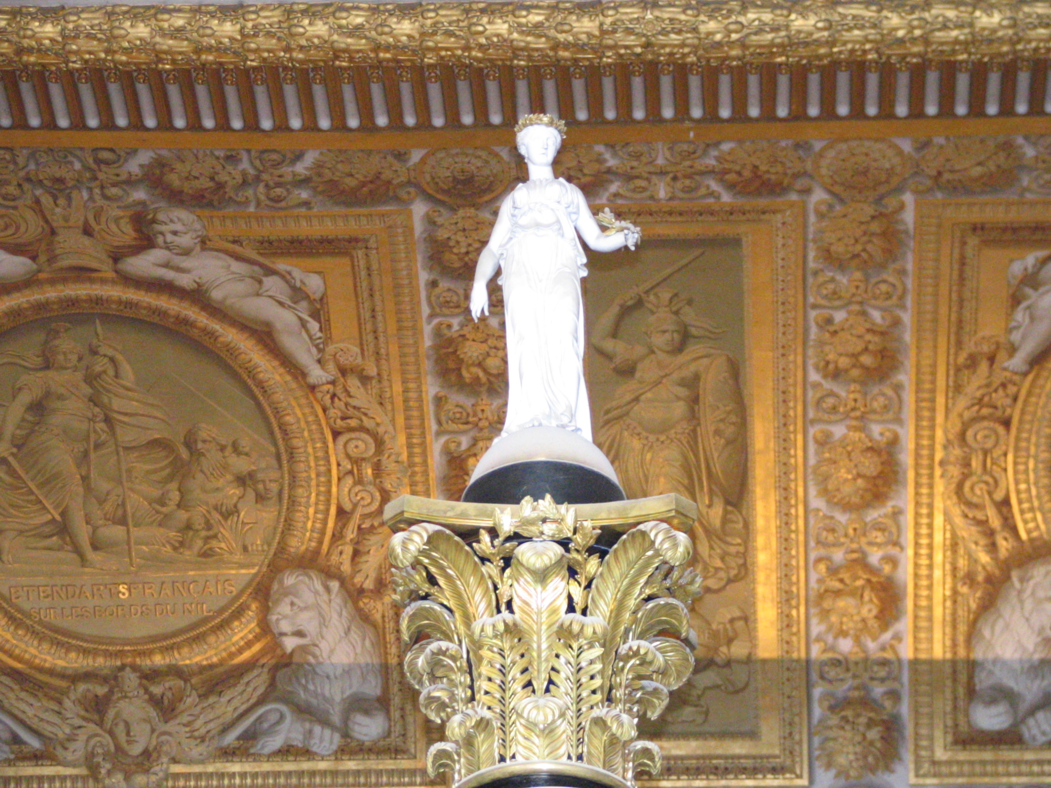 an ornate gold painted ceiling with a statue in the center