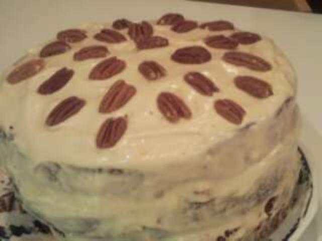 this cake has a white frosting and some pecans on top