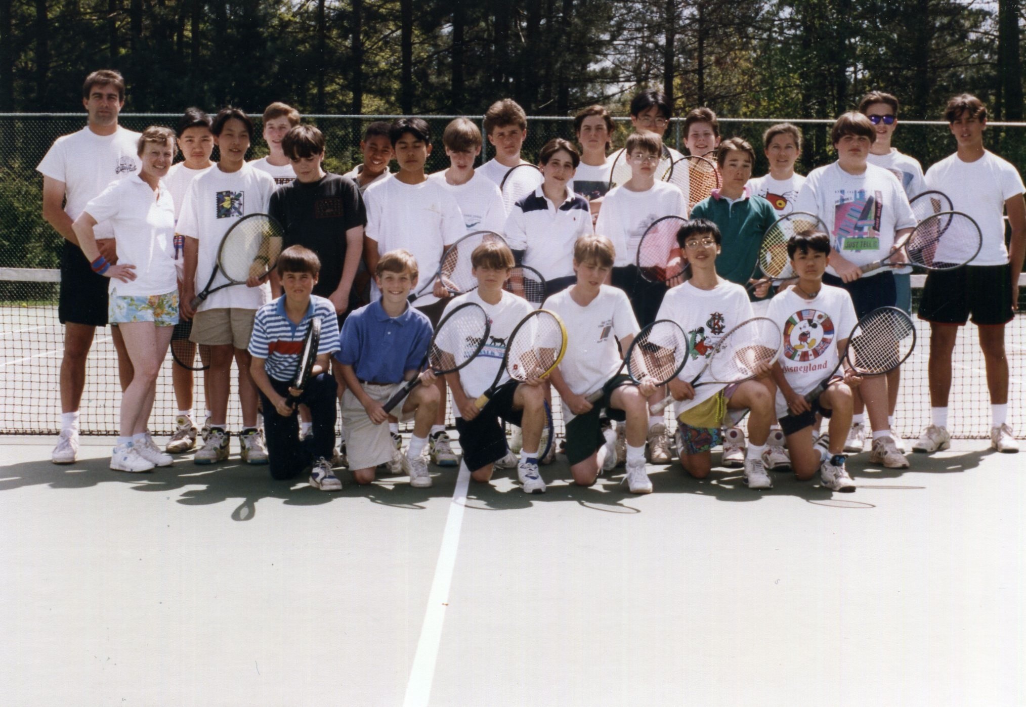 a large group of people holding rackets on a tennis court