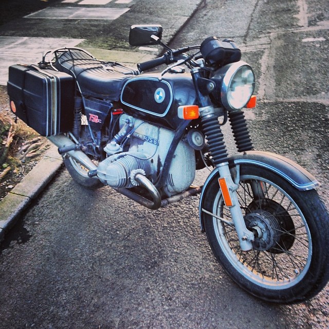 the old motorcycle is parked on the side walk