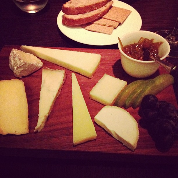 a wooden tray topped with different types of cheese