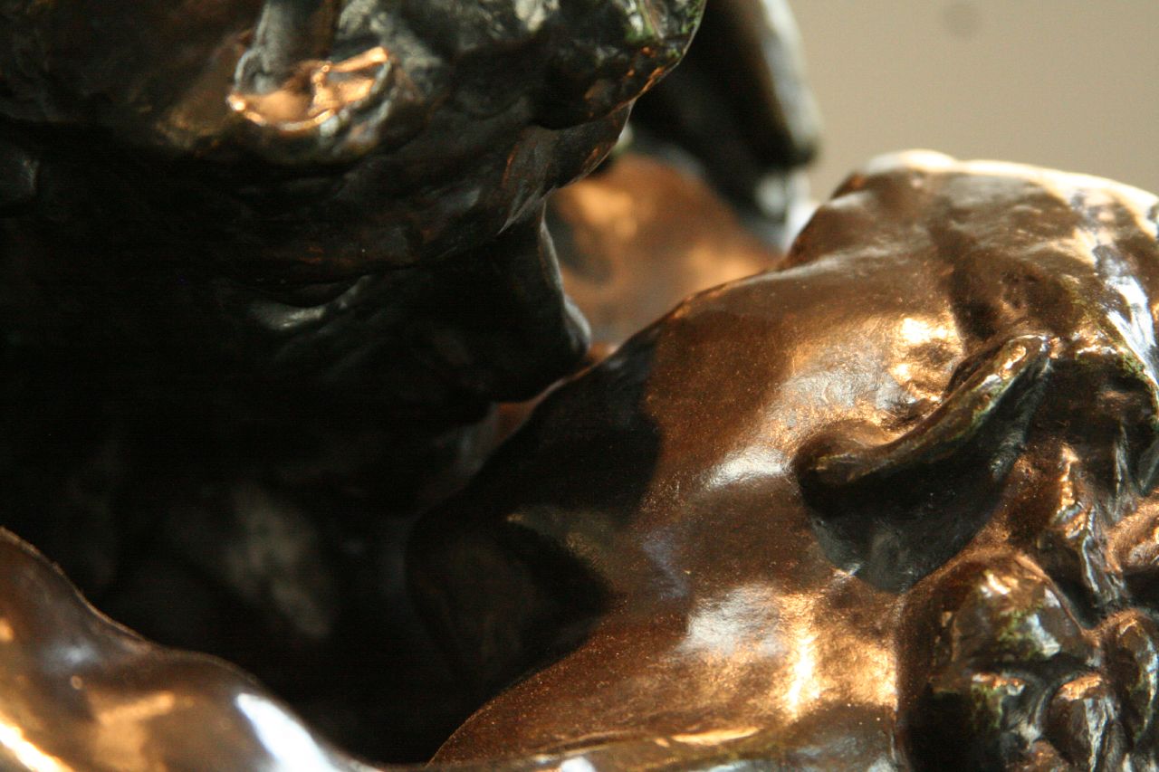 the hands of an antique bronze figure on display