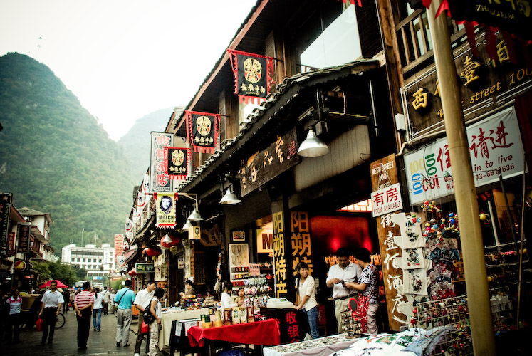 shoppers are browsing the outdoor market with mountains in the background