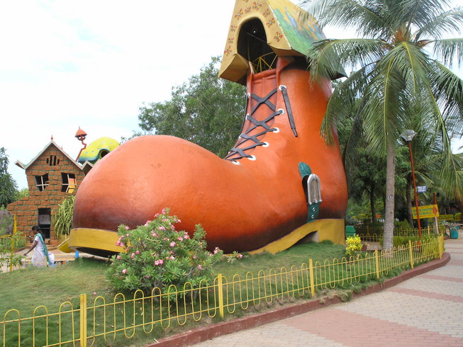 a large orange boot sitting in front of some palm trees