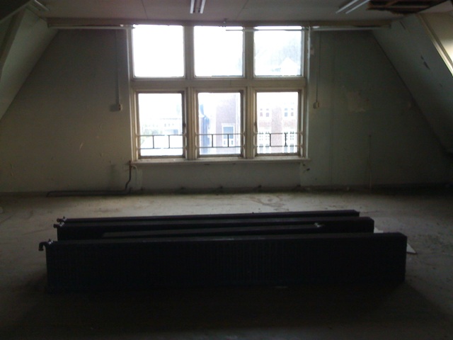 empty loft with two large windows, an attic door and no curtain on them